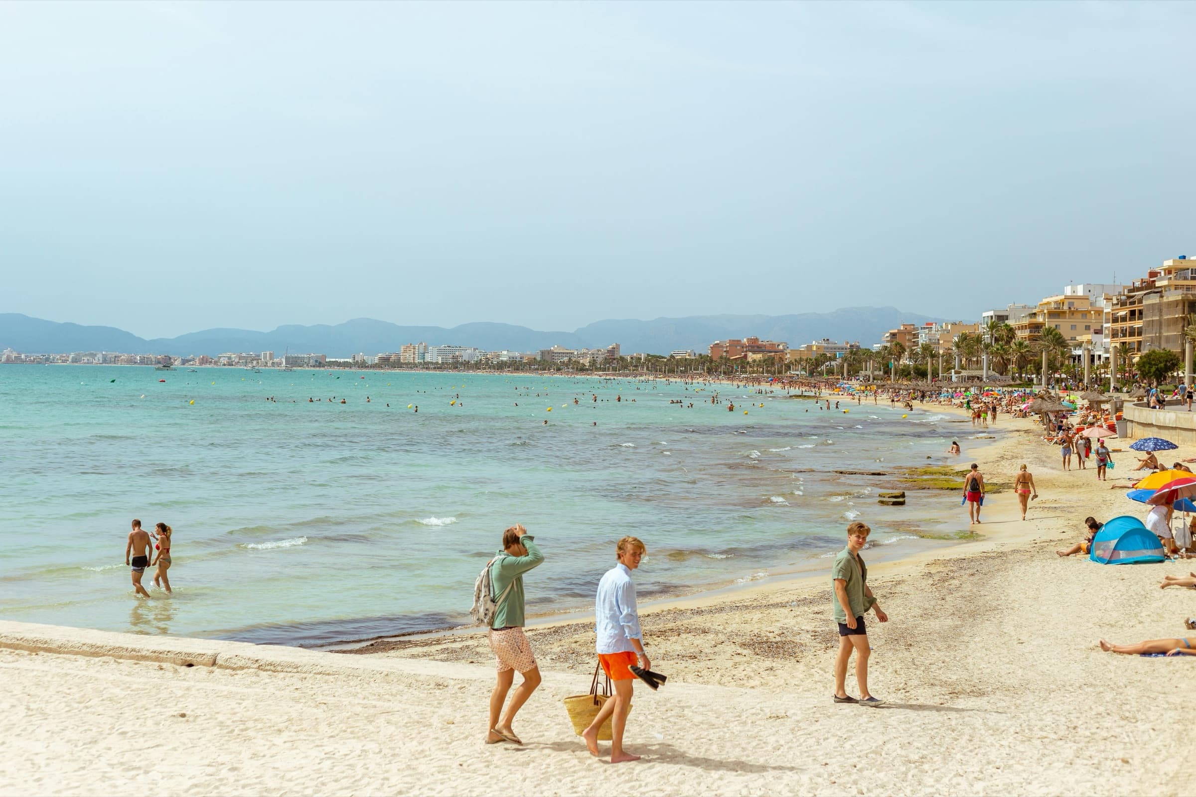 Beachgoers on Palma's seafront with the Tramuntana mountains in the distance